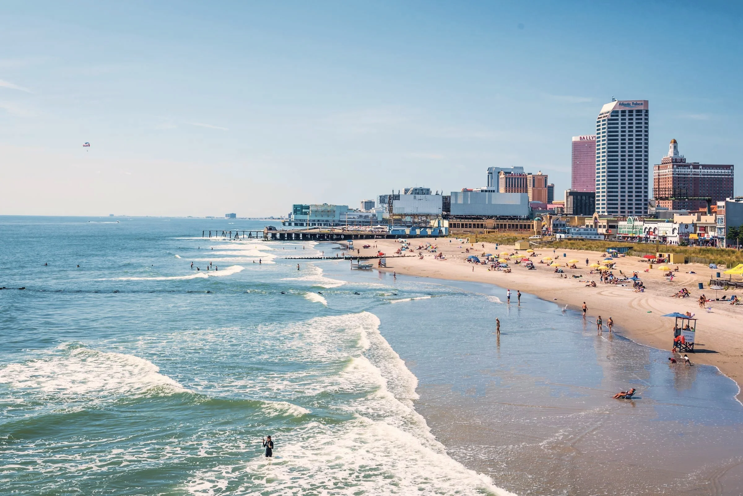 Waves rolling onto a wide Atlantic City beach, with the boardwalk skyline behind